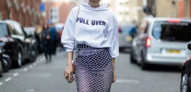 Frau trägt ein Hoodie-Sweatshirt mit einem taillierten Midi-Netzrock