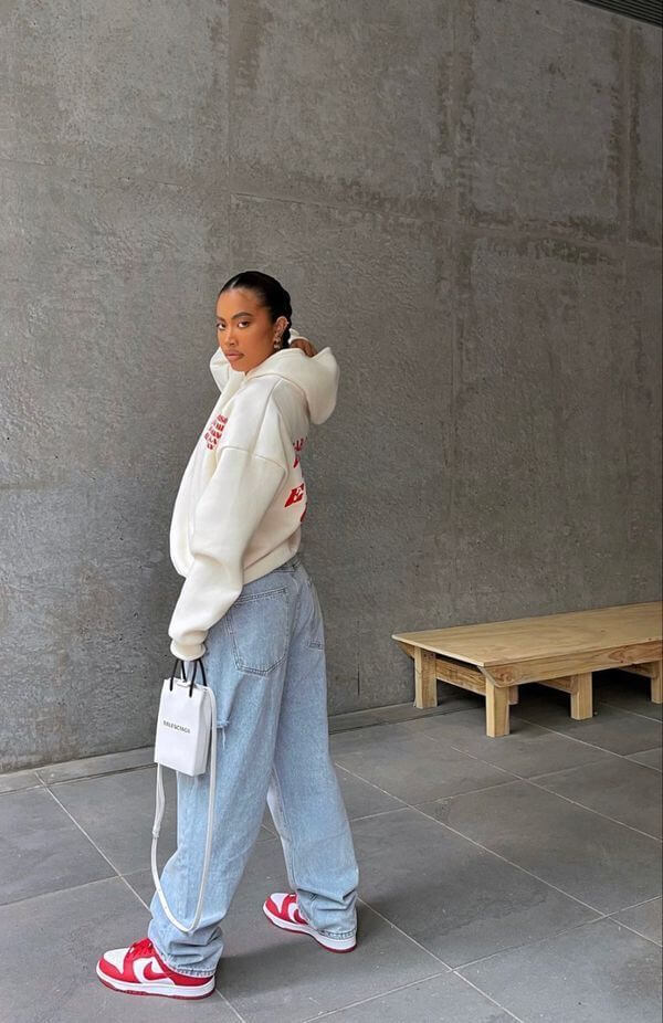 Frau, die ein weißes Sweatshirt und eine Boyfriend-Jeans mit Sneakers trägt