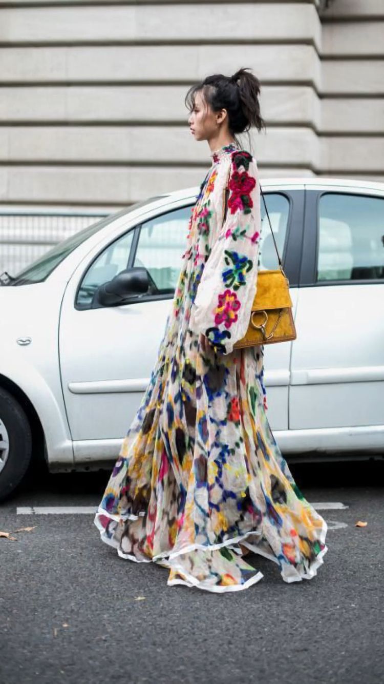 Frau, die ein langes Blumen-Kleid auf der Straße trägt